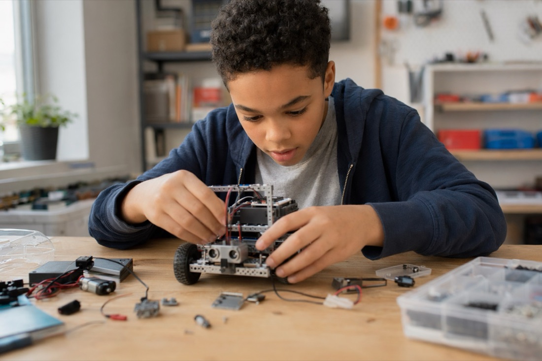 A young student examining a small programmable robot they just built.